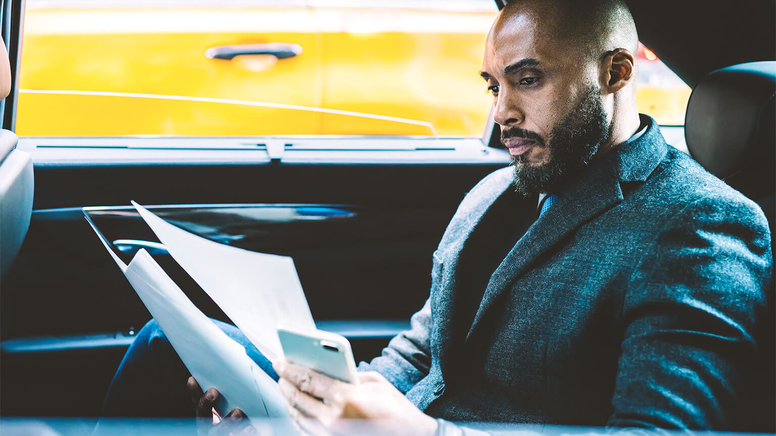 A banker reviewing reports on different economies around the world, while being chauffeured to their office