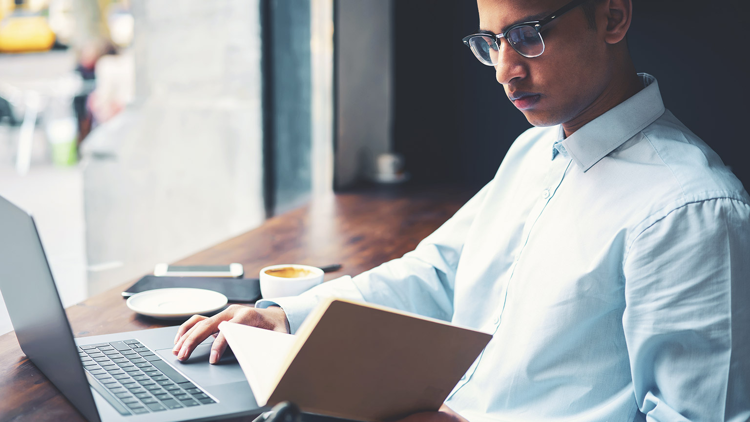 A design student reading online material and writing notes