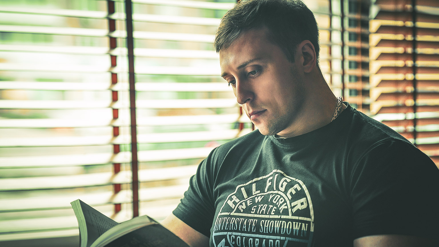 A youth worker sitting by a window reading a book