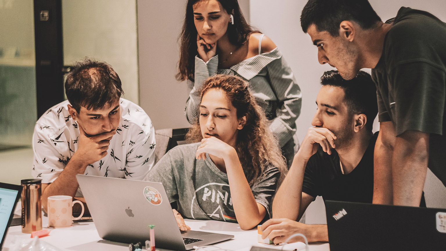 A group of programmers looking at a project on a laptop