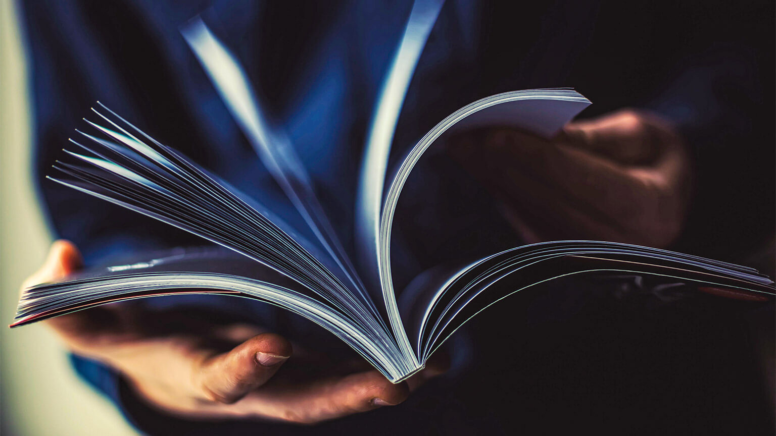 A person flicking through a large magazine, scanning for interesting articles