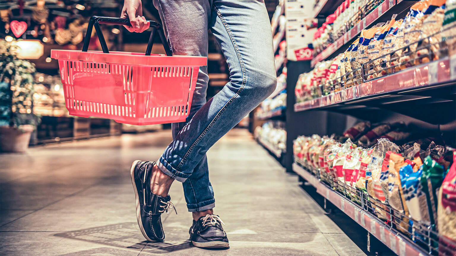 A peron standing in a supermarket aisle, looking at the many different products on offer to them