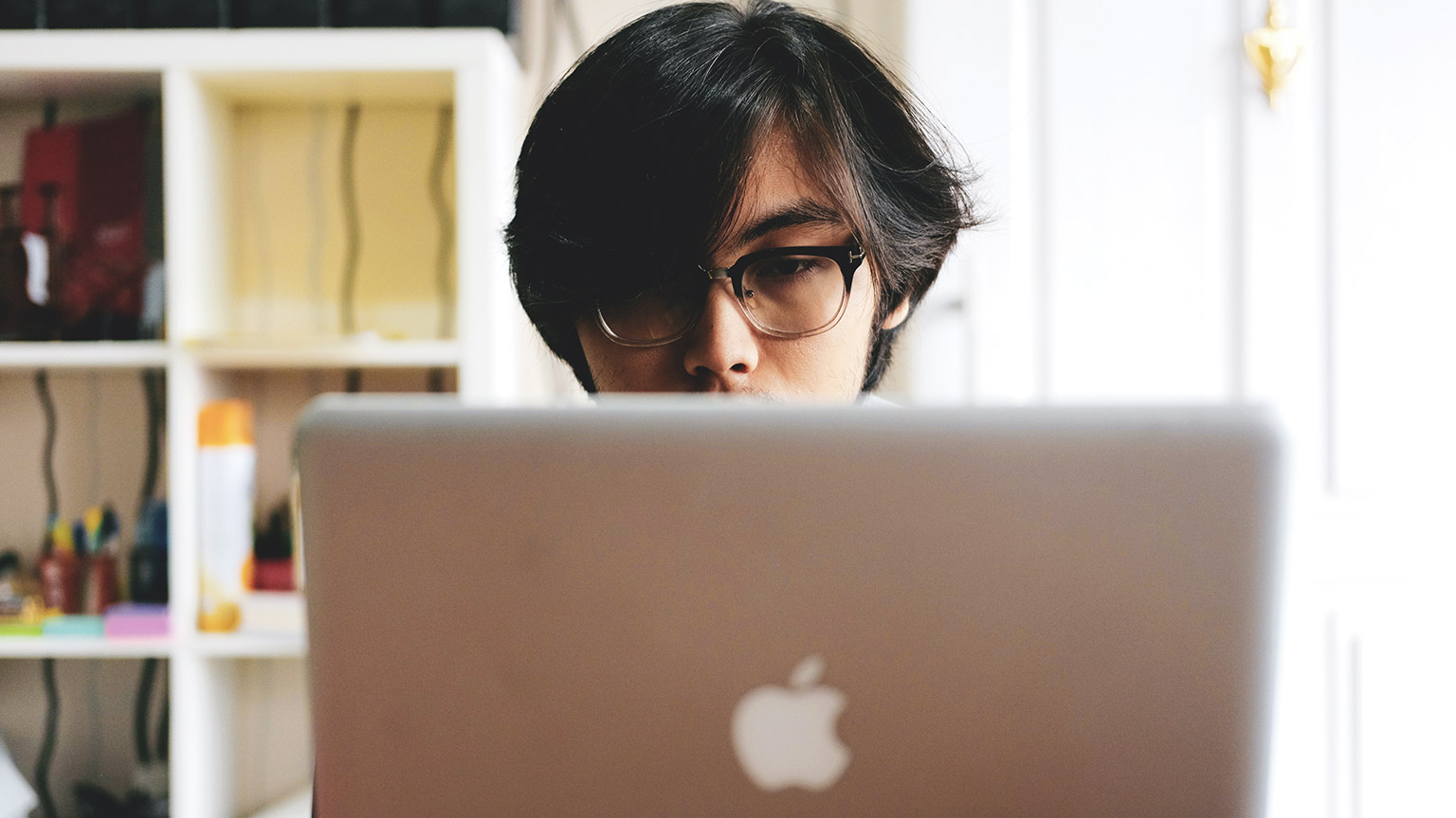 A close view over the laptop of a designer working intently on a project they've recently been assigned