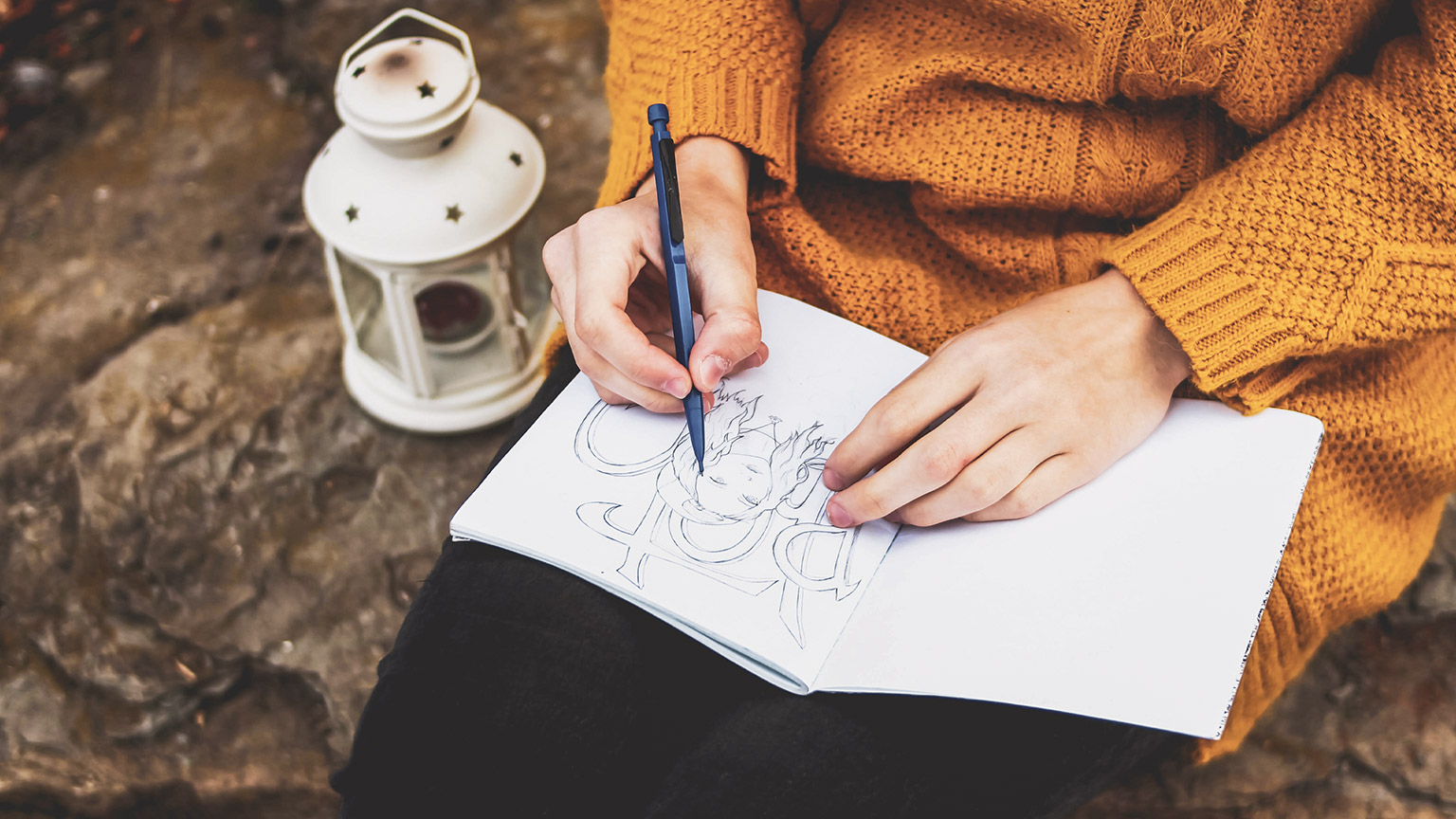 A close view of an illustrator sketching on a notepad