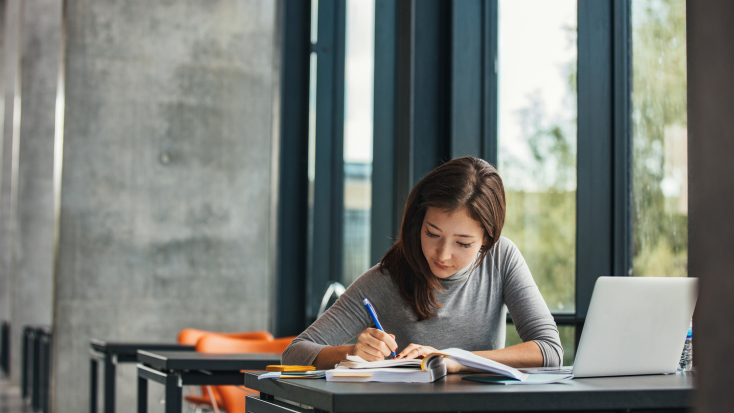 Shot of young asian female student sitting at table and writing on notebook. Young female student studying in library.