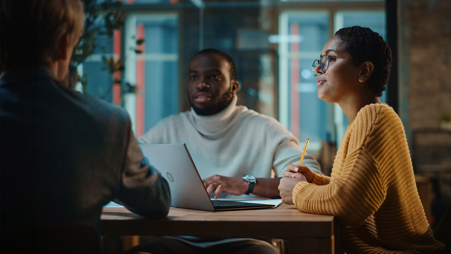 A group of IT staff sitting at a desk discussing operating systems