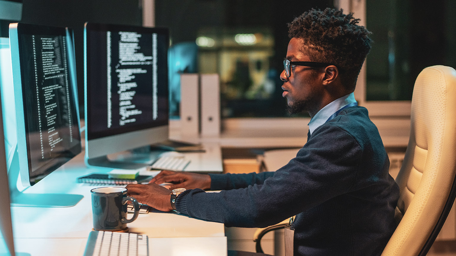 A programmer working on a desktop computer with multiple screens