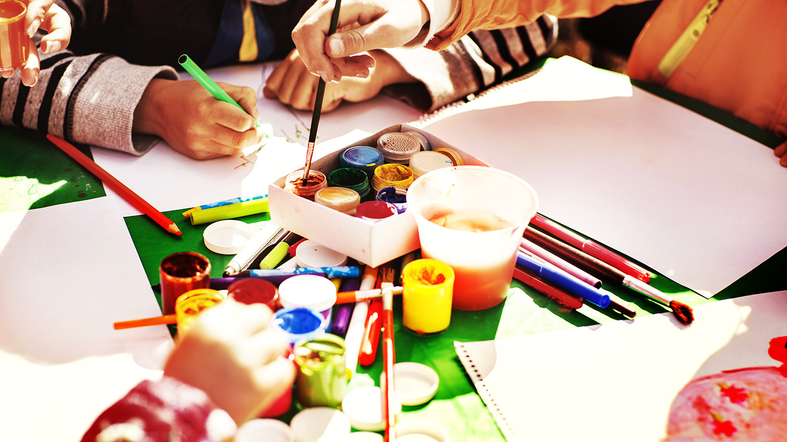 Children dipping their paint brushes before applying on blank paper 