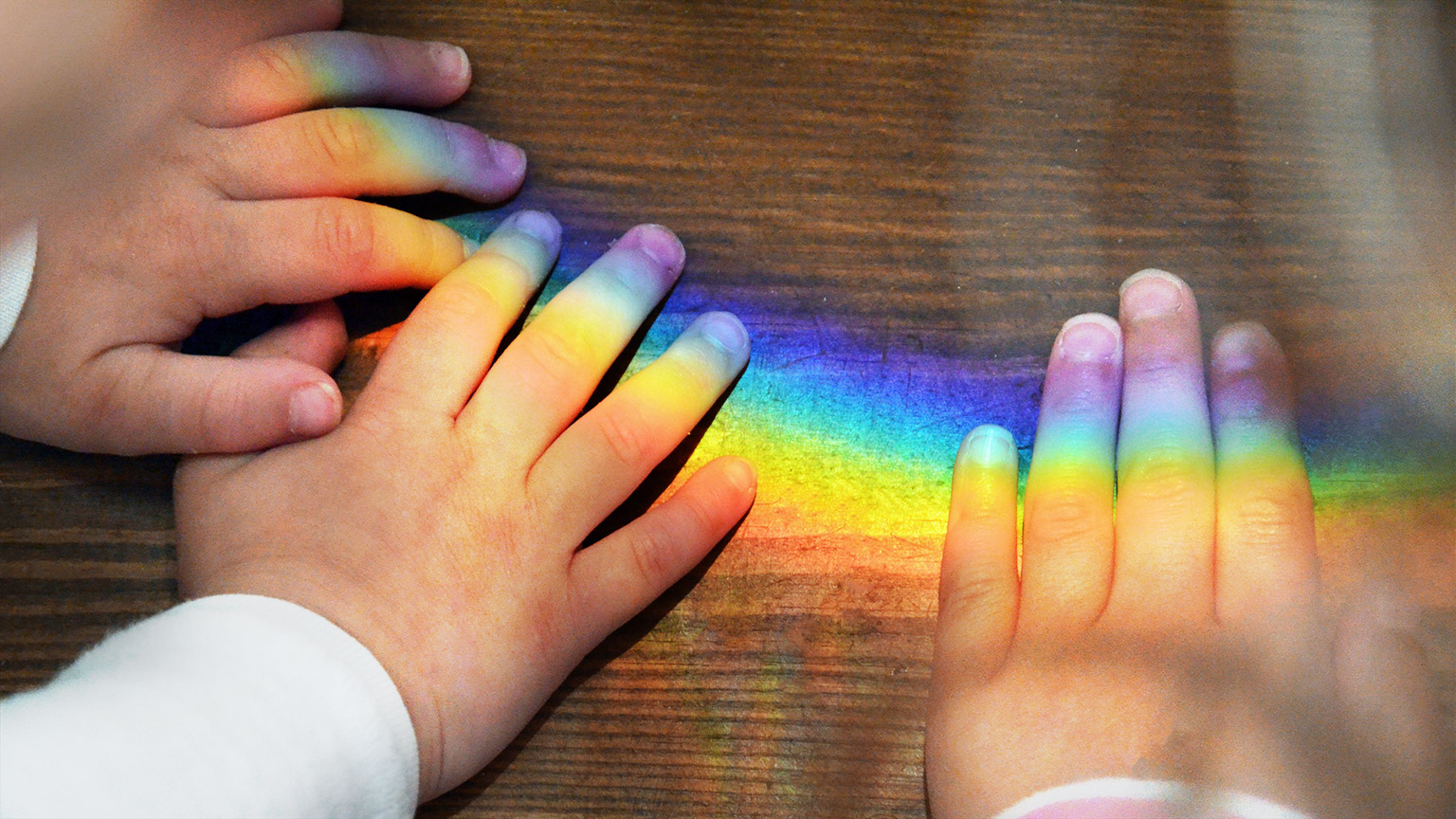 A spectrum of colours shining down on children's hands