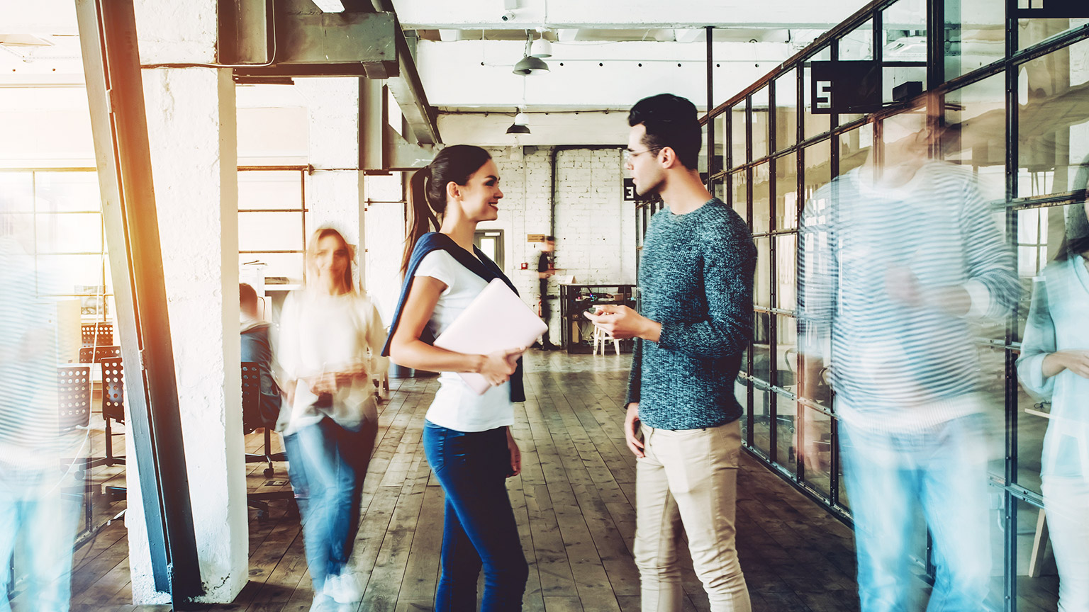 Two colleagues introducing themselves to each other in a busy office space