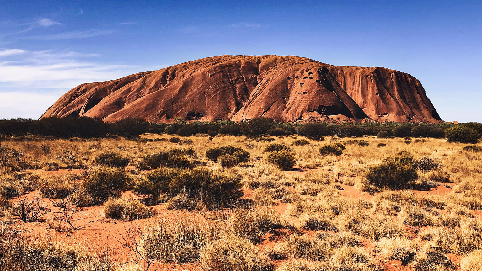 Ground level view of Uluru on a clear, sunny day