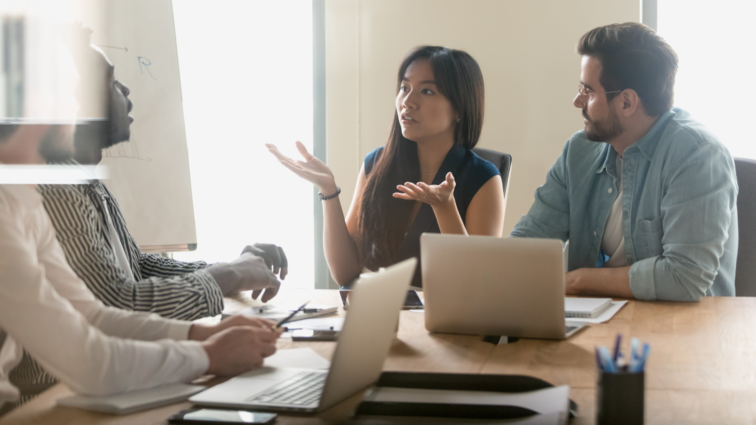 Annoyed diverse employees arguing in boardroom due to cross-cultural misunderstandings