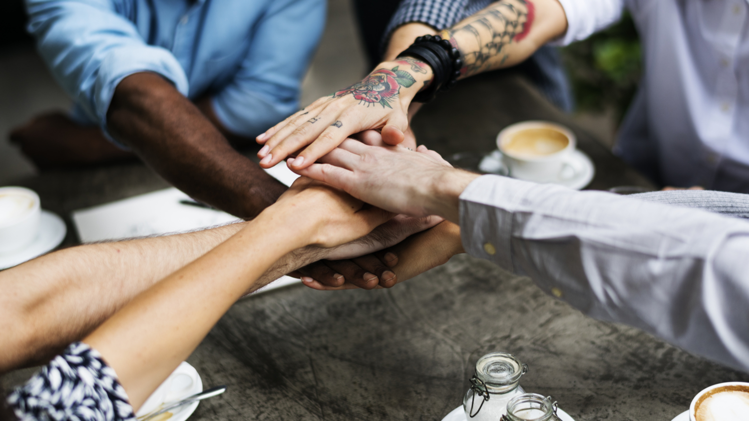 Group of diverse co-workers, stacking hands on top of each others as a team