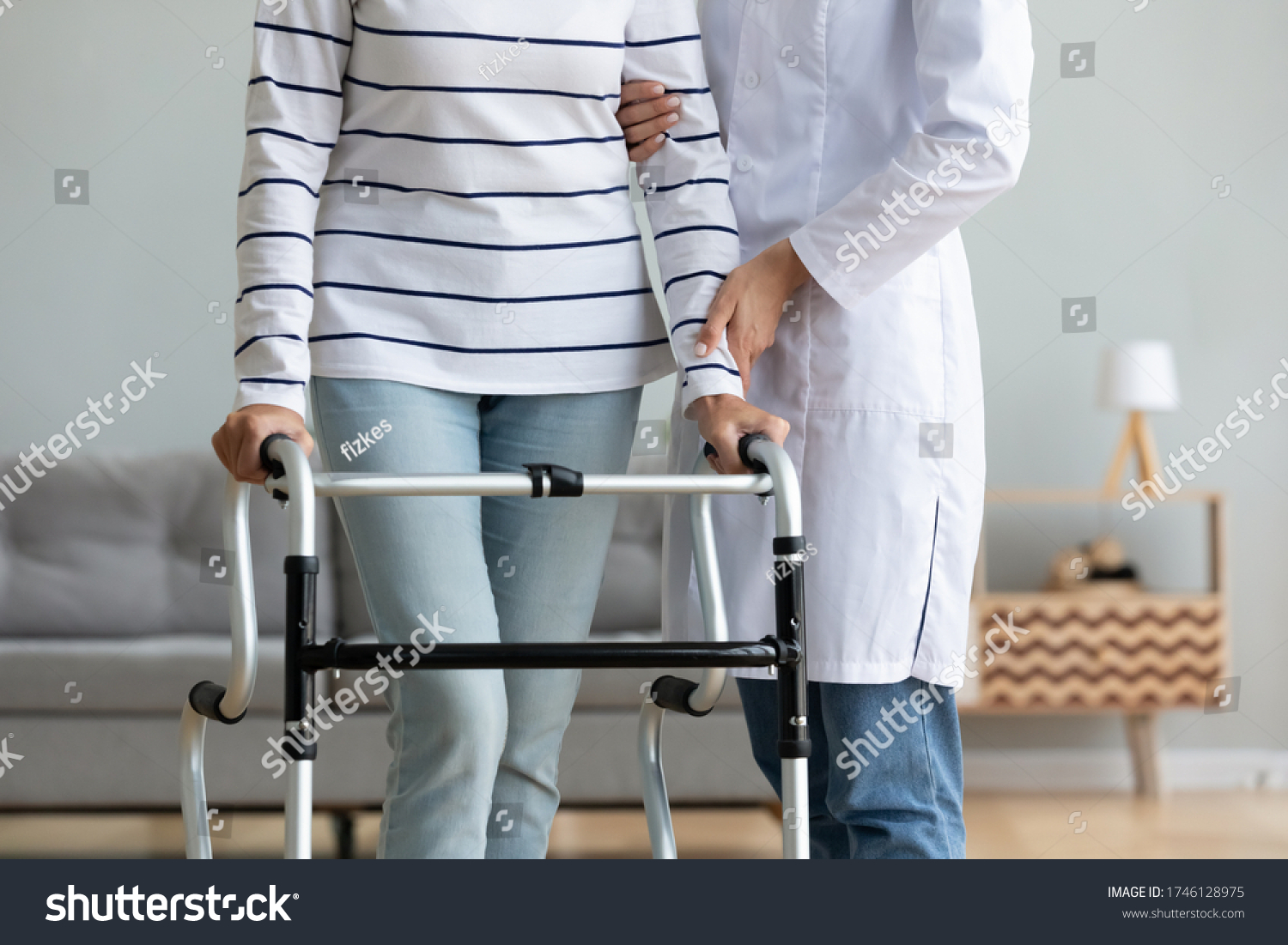 caregiver helping to disabled aged female patient walk with walker physical therapist