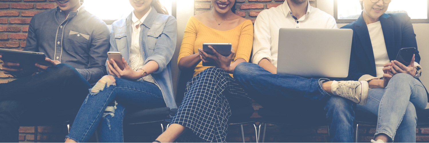 People sitting in a row using mutliple devices