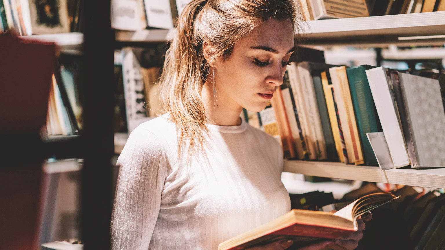 A student spending some time in the local library, absorbing reference material for their class project