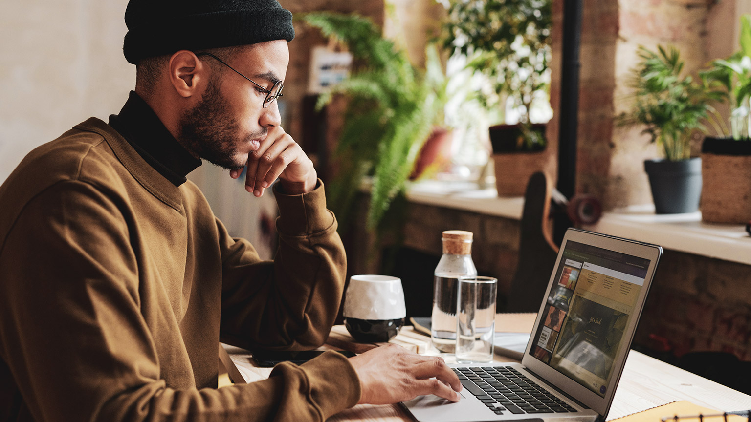 A designer sitting at a desk reviewing a website design