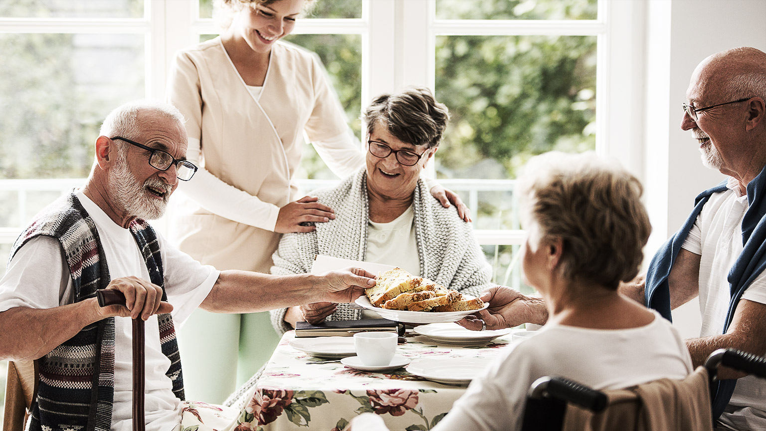 A group of elders being happily taken cared for by a carer