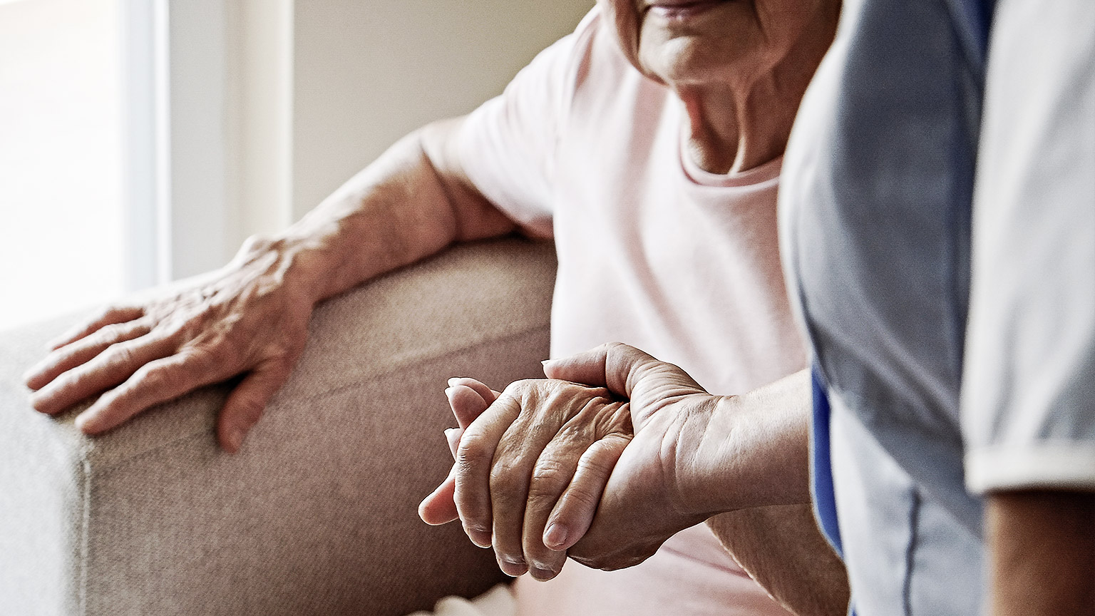 A carer helping an elderly up from a chair