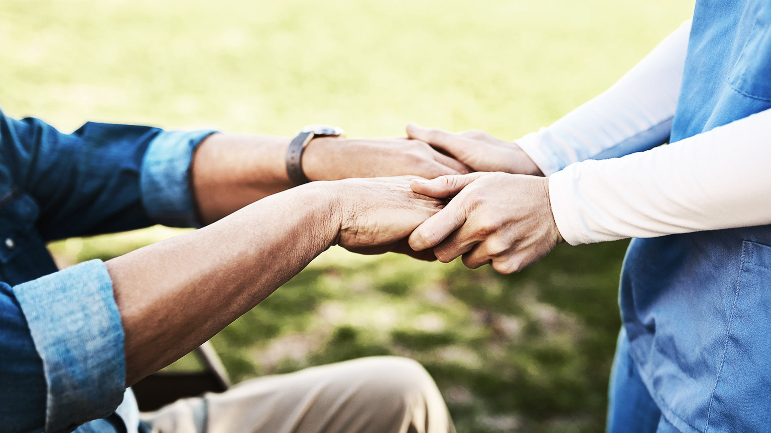 A healthcare person holding an elderly's hand