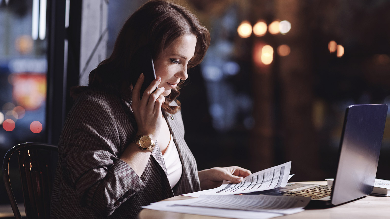 An accountant working in a cafe while talking on the phone