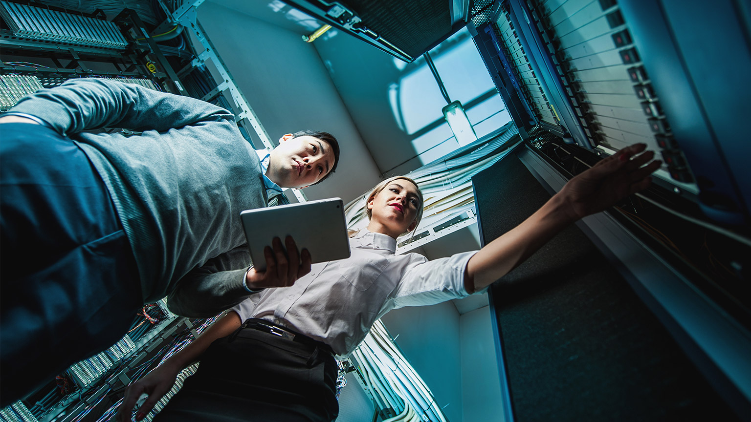 2 system engineers examining hardware in a computer server room