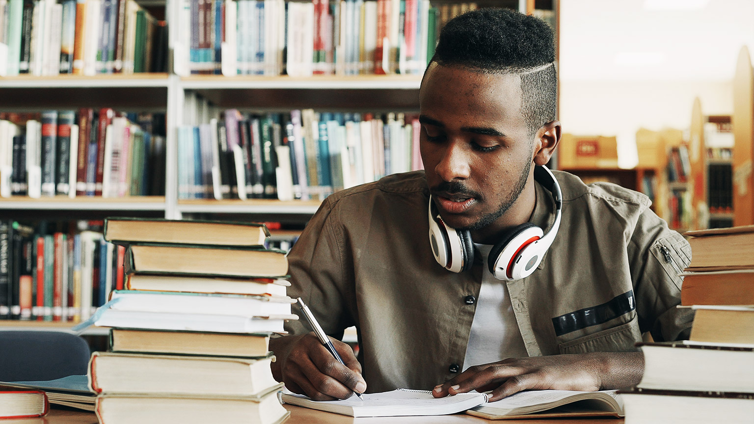 A student studying and taking notes in a library