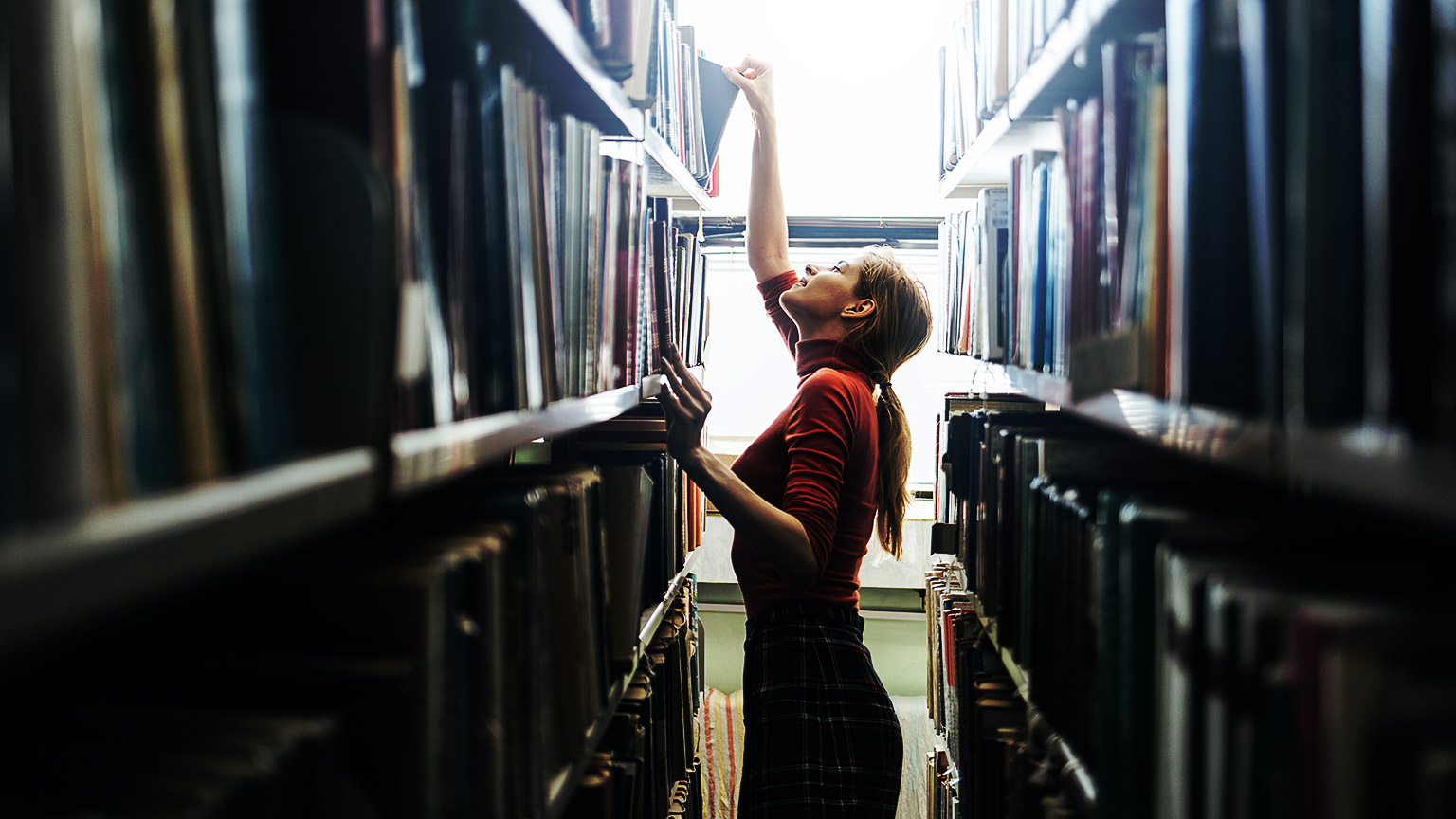 A person reaching for books in a library