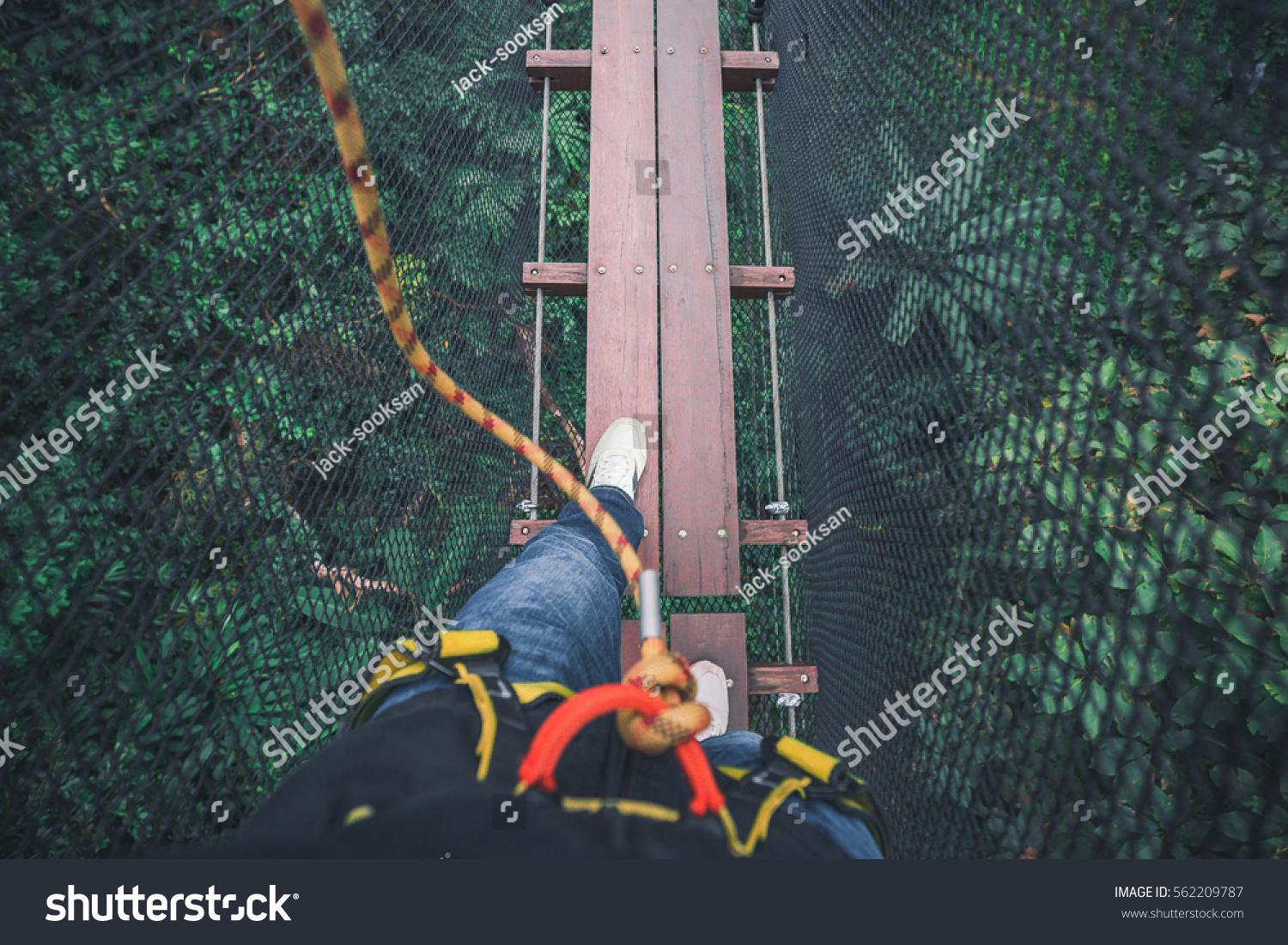 personal walking on wooden bridge with harness with net under bridge