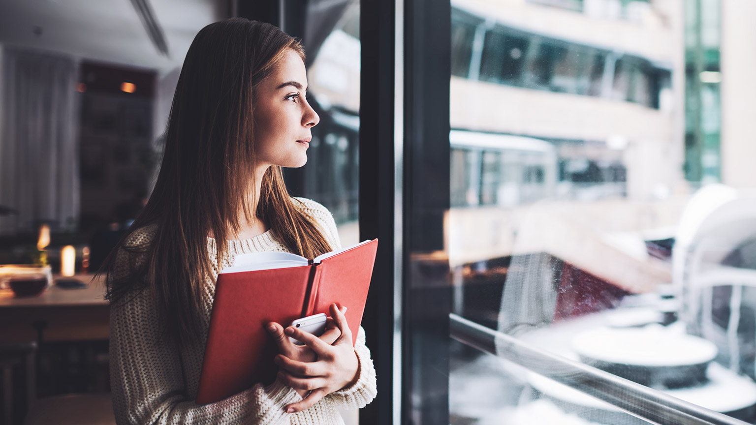 A student standing in a library looking out the window