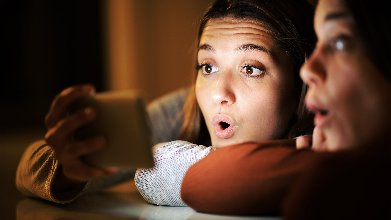 Two people holding a phone and being surprised at what they're seeing