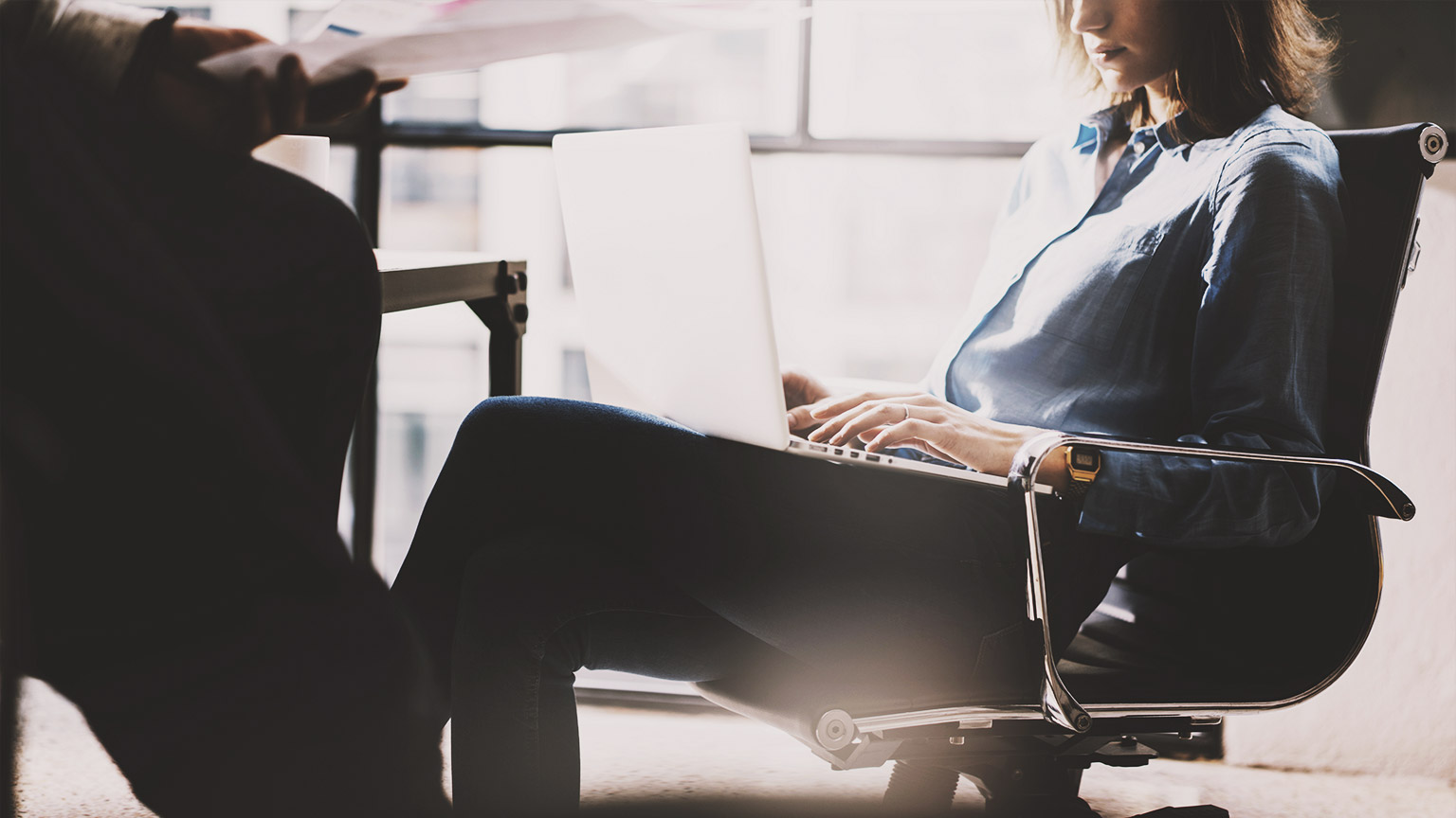 A data analyst sitting at a table in a modern office working on a data project