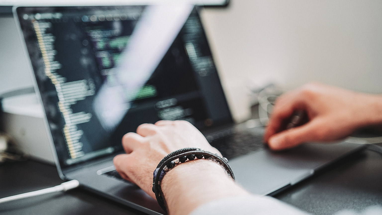 A close view of an IT person working with code on a laptop