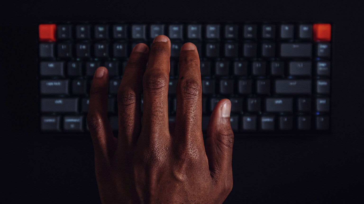 A person tapping their wireless keyboard's keys, attempting to wake up their computer