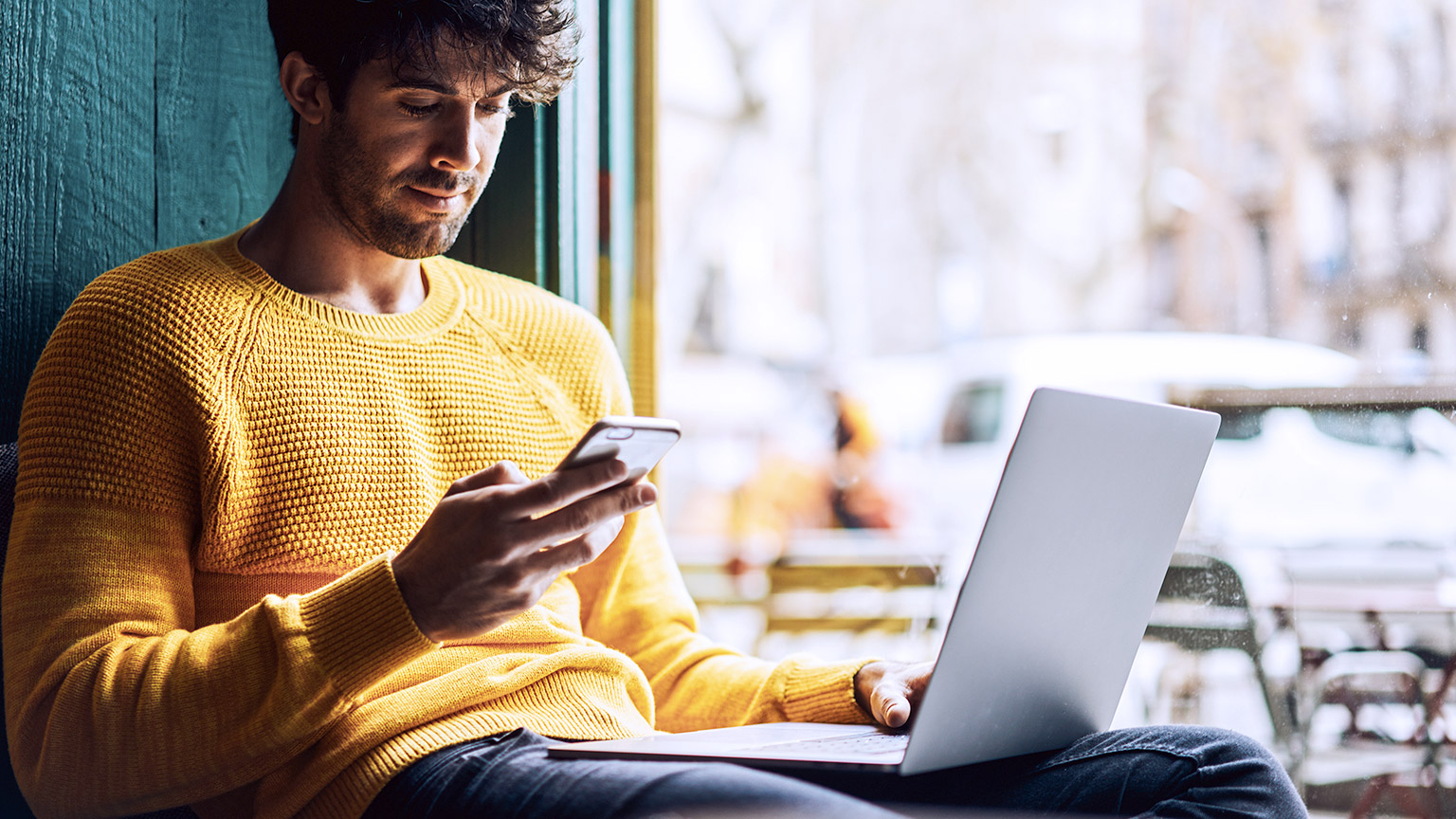 man using phone and laptop