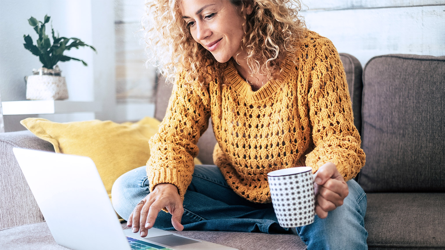 woman holding a mug while working with a computer