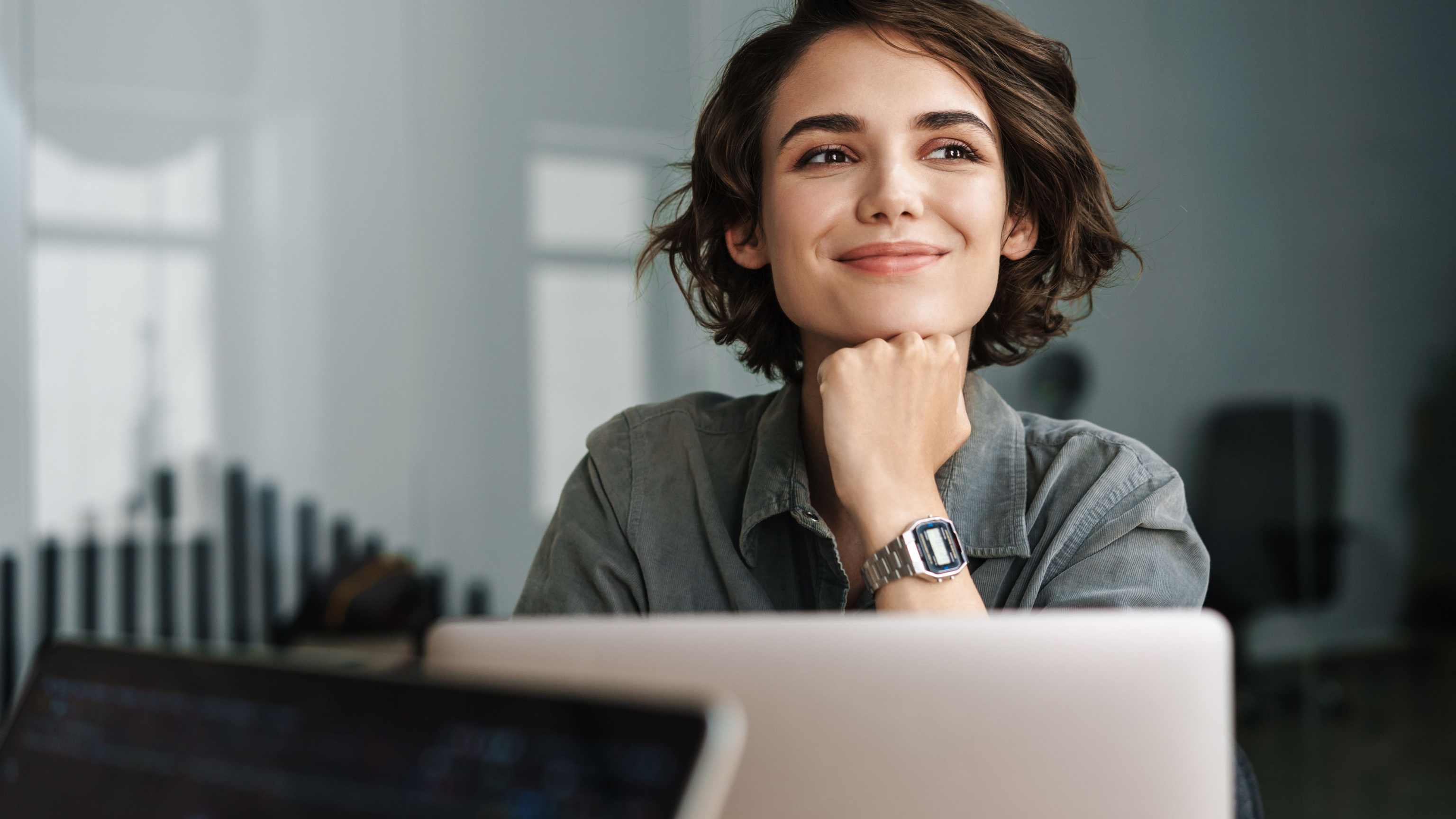 Image of young beautiful joyful woman smiling while working with laptop in office