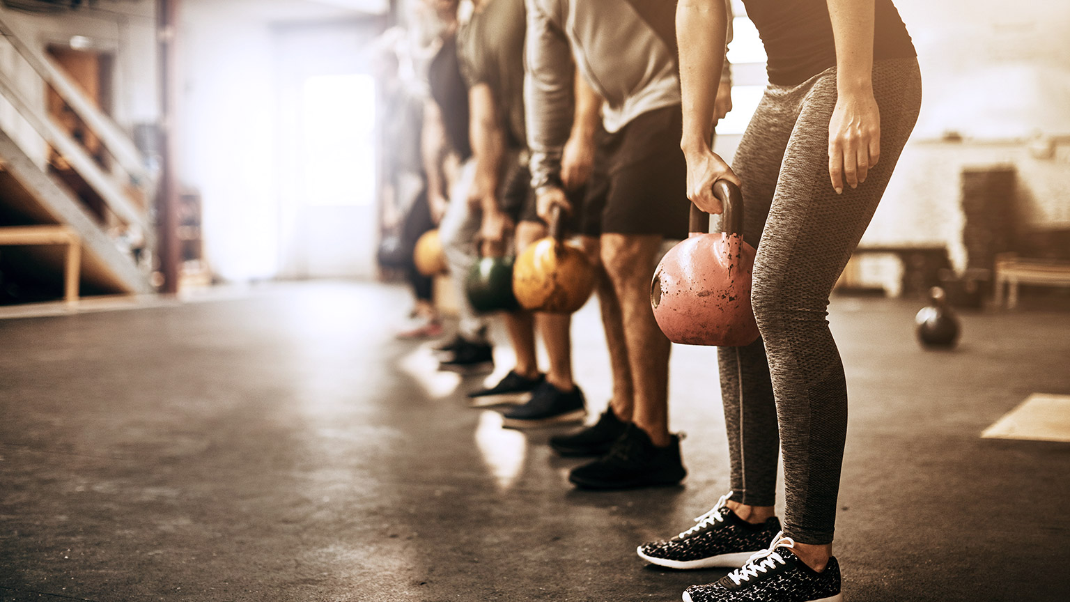 ding in a row holding kettlebells during an exercise class at the gym