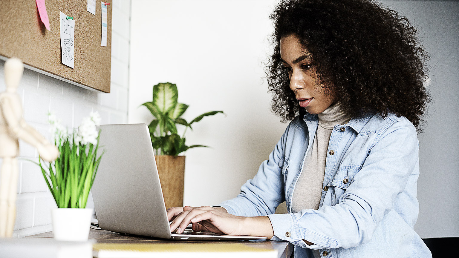 A woman working intently at her laptop on her home desk