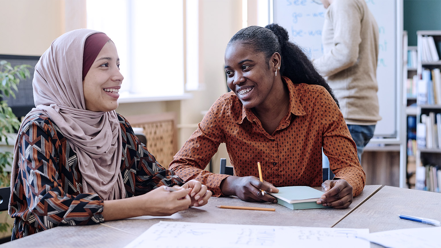 Black woman and Middle Eastern woman happily chatting