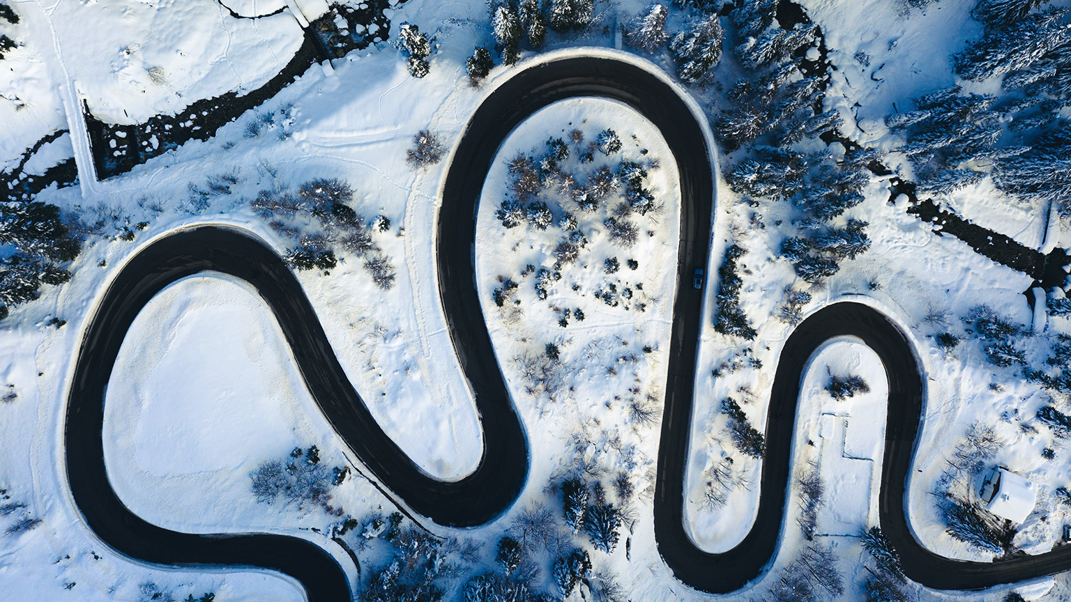 A top down view of a twisting road surrounded by snow