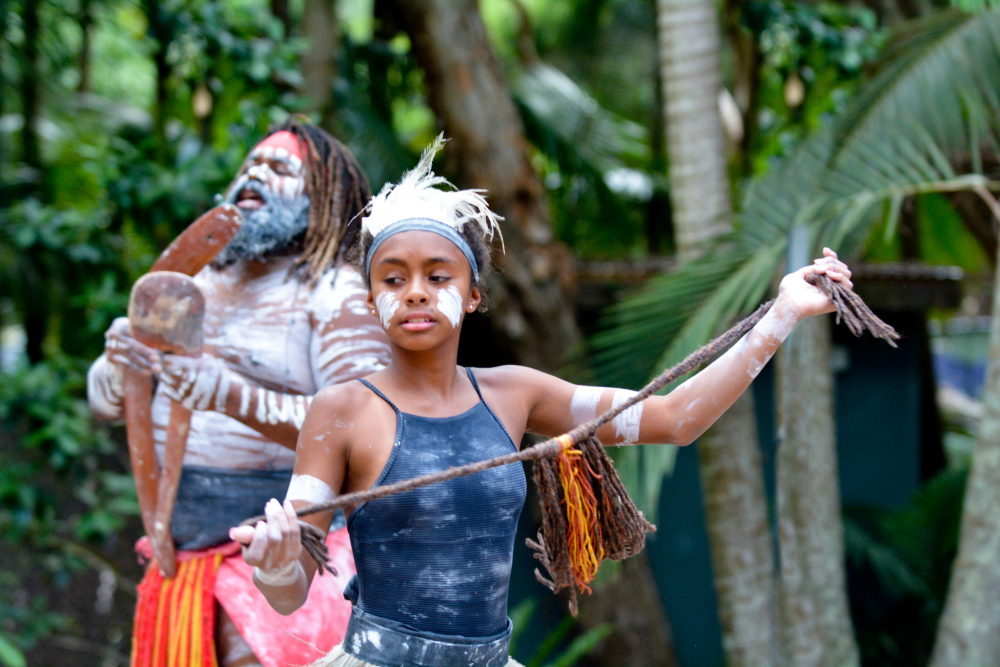 Young adult Australian Aboriginal woman dancing to the singing rhythm sound of Australian Aboriginal adult man in the tropical Queensland, Australia.