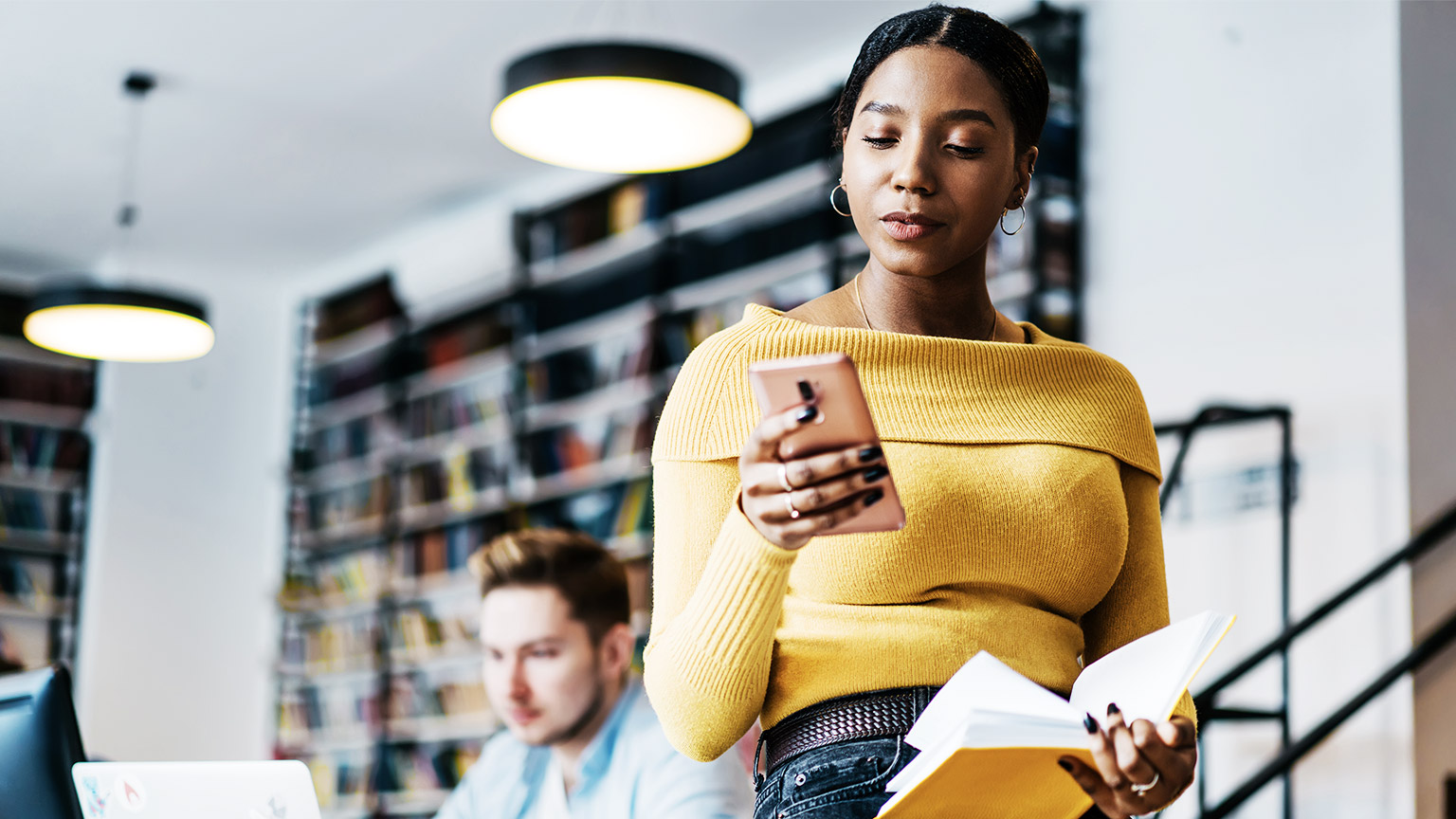 Woman sitting on the table while looking at the phone inside the library