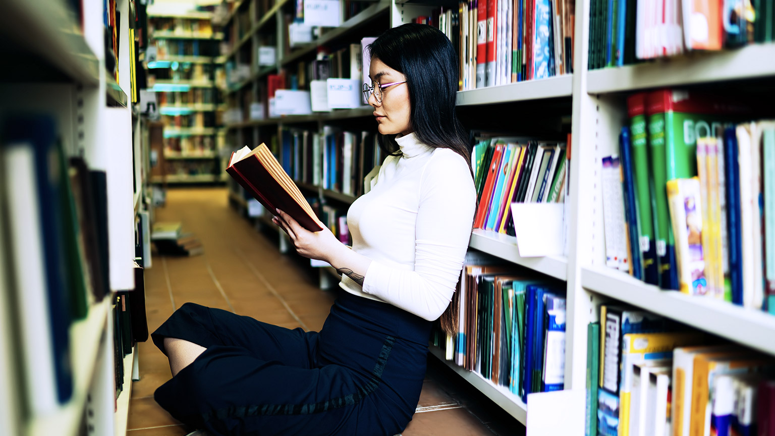 Woman sitting on the floor while reading inside the library