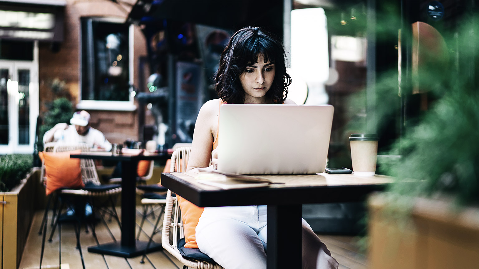 A person using a laptop outdoors in a cafe