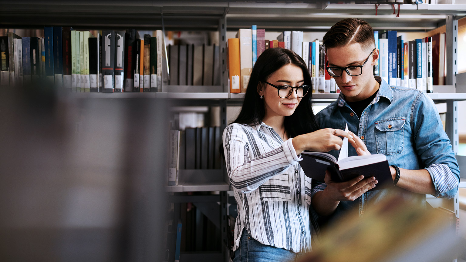 Man and woman browsing books inside the library