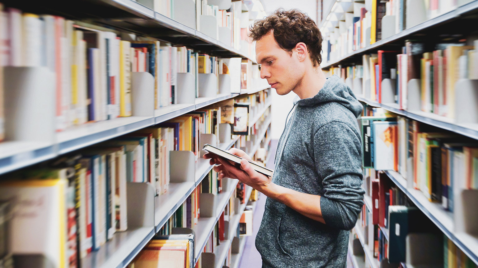 A young person reading reference materials in a library