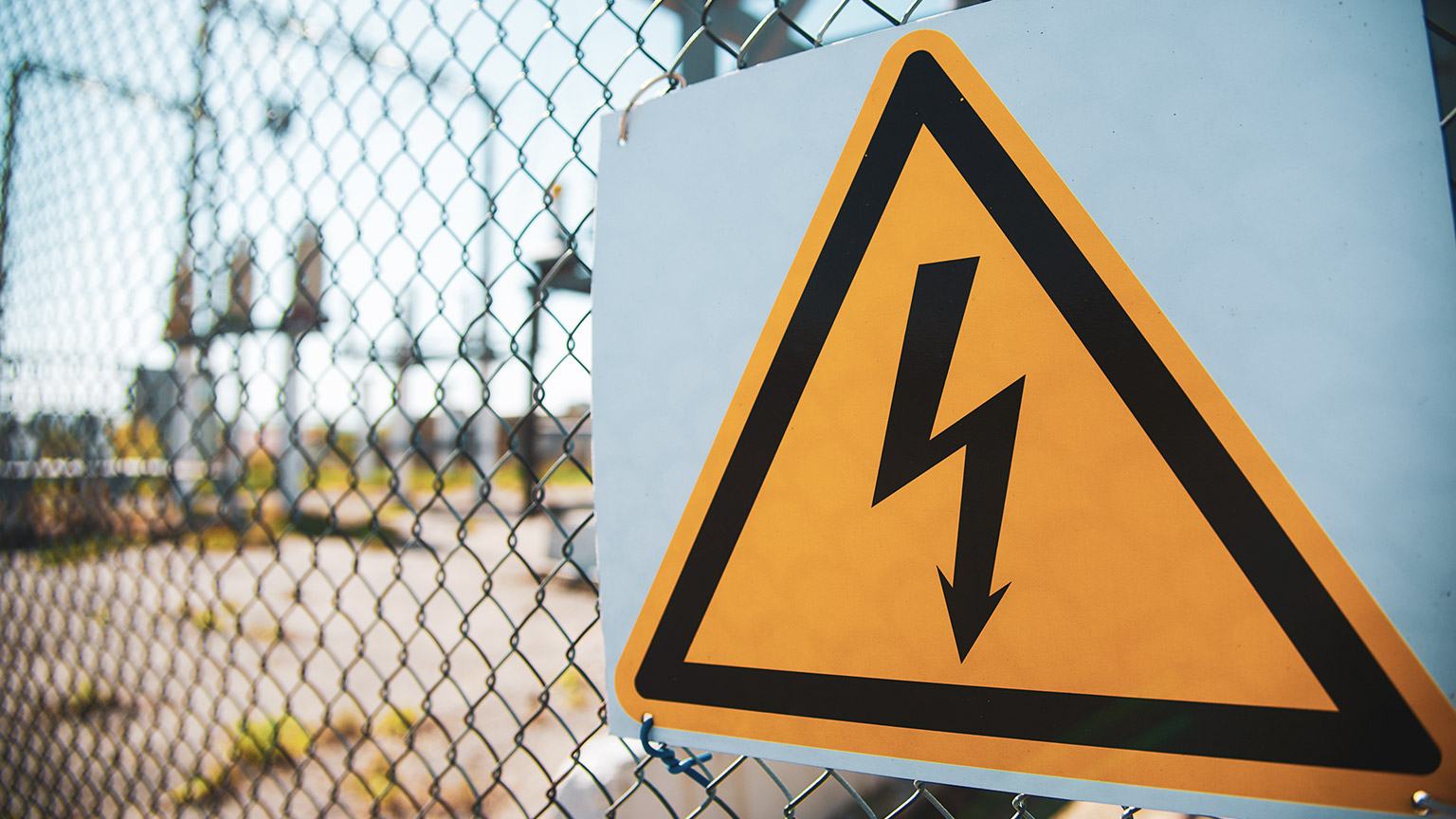 A close view of a high voltage warning sign on a fence