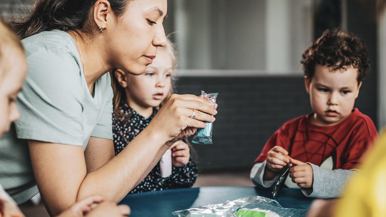 A teacher helping kids with materials in a childcare setting