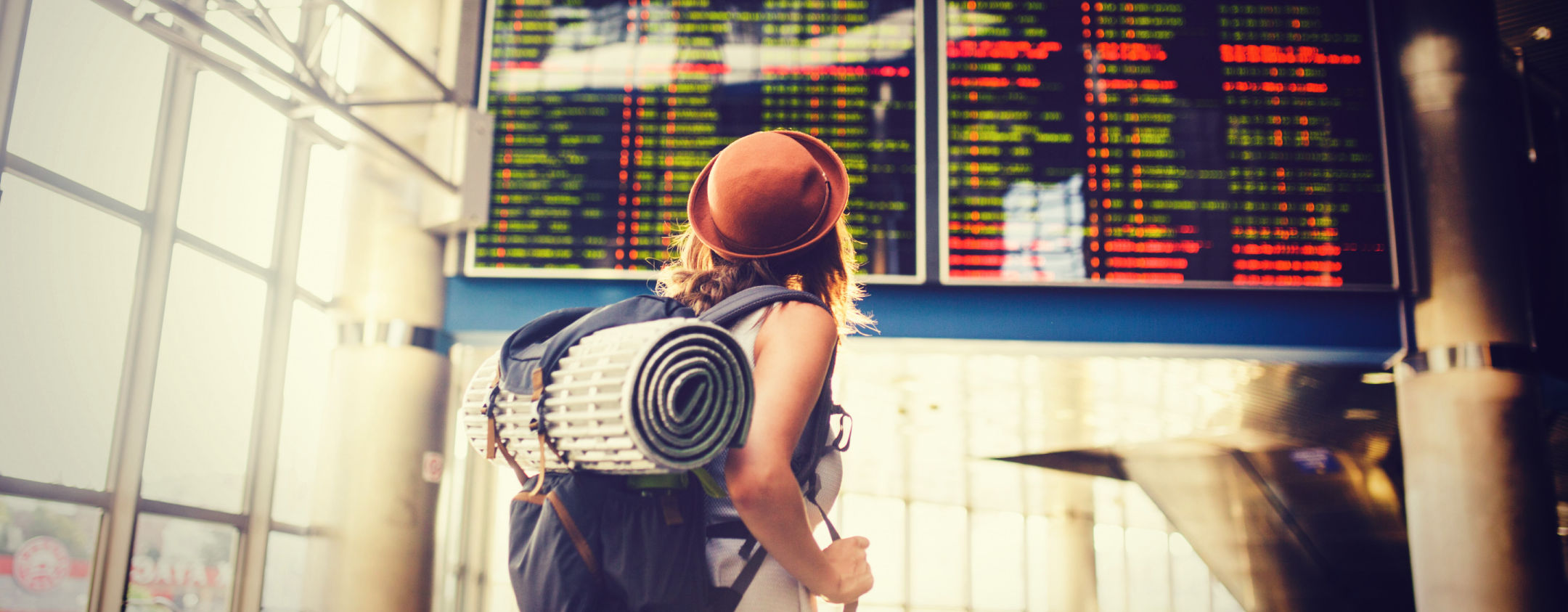 Backpacker at an airport looking at a flight departure board